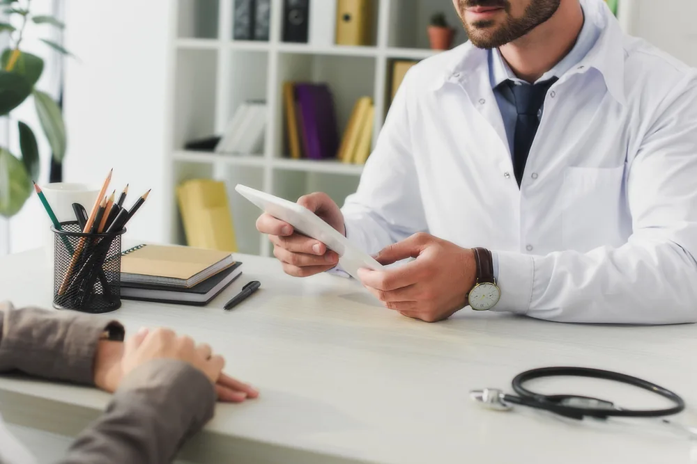 Doctor talking to patient over desk discussing a transitional care plan