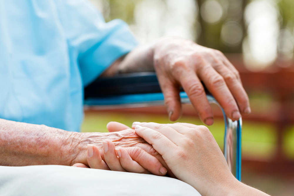 Compassionate elder care manager holding hands with a senior in need of medical attention.