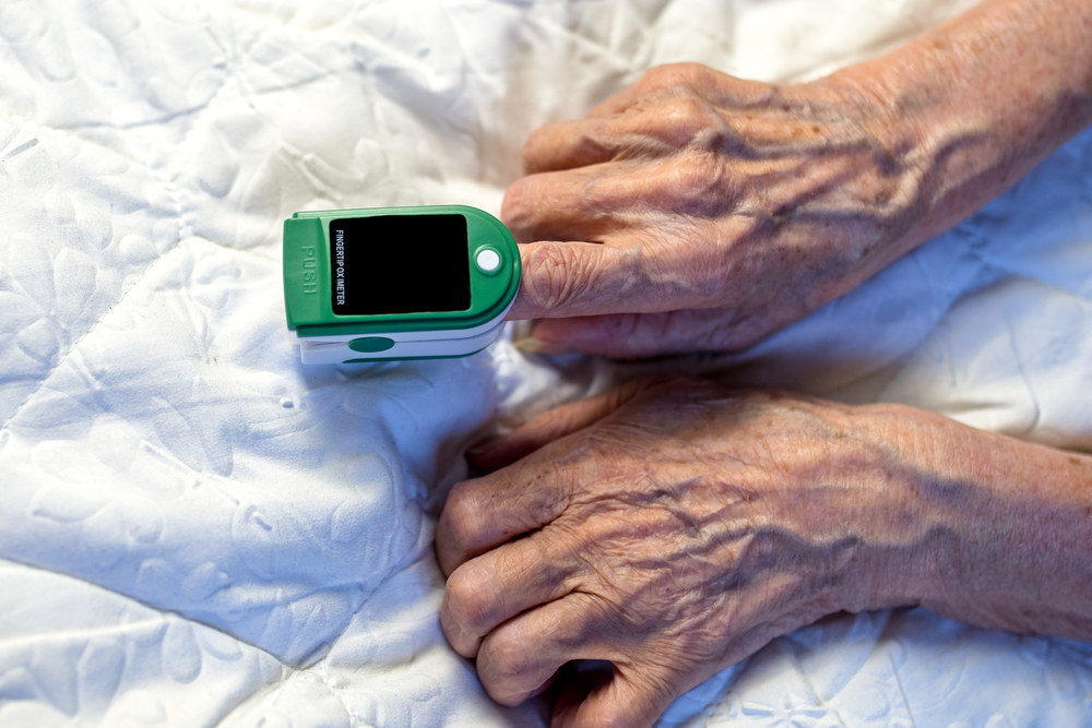 A person with chronic illness checking pulse and oxygen in bed