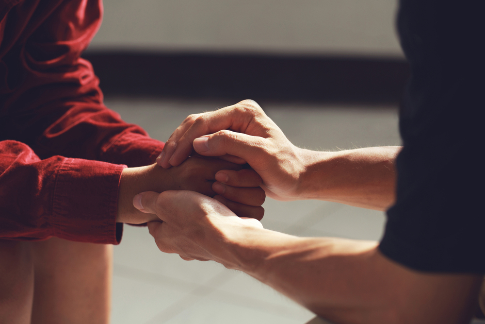 Care manager holding hands with an adult who has disabilities.