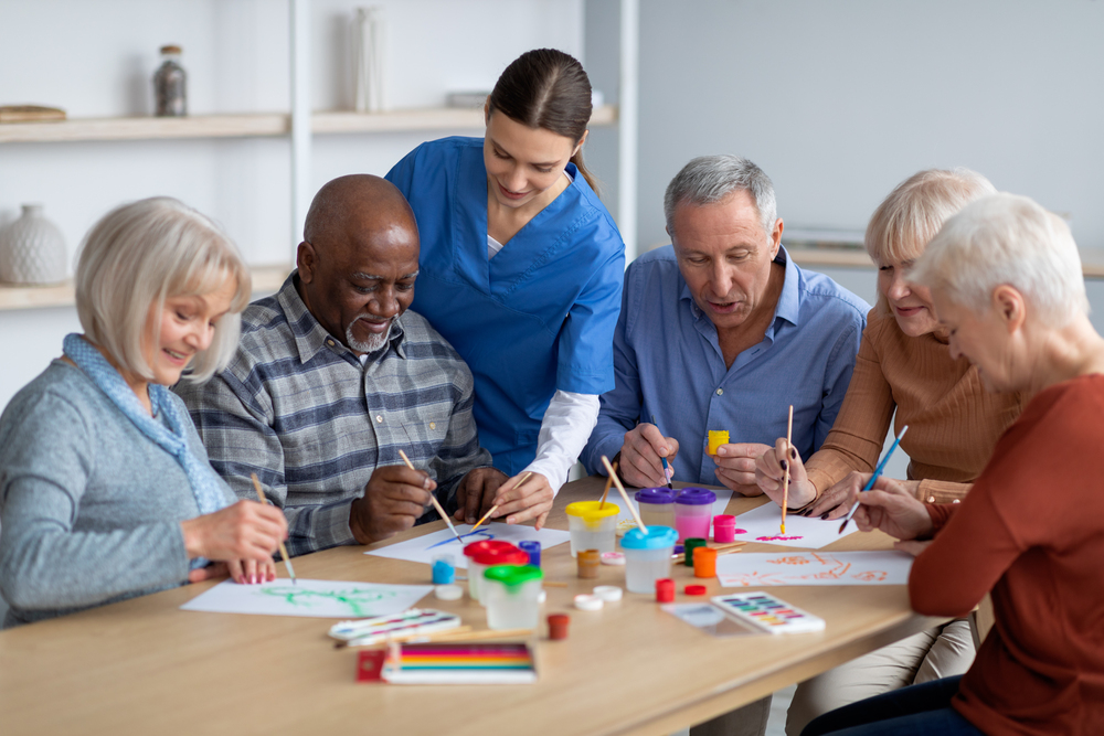 Seniors doing art therapy with a caregiver