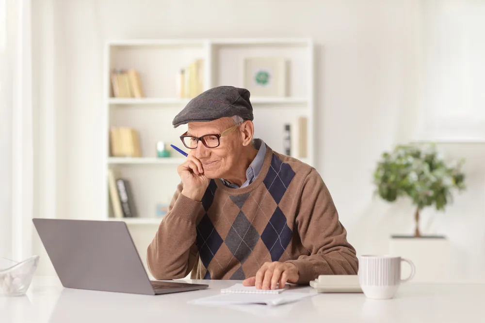 Elderly man with a laptop studying his transitional care management program