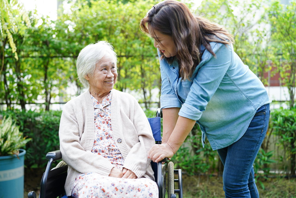Caregiver help Asian elderly woman disability patient sitting on