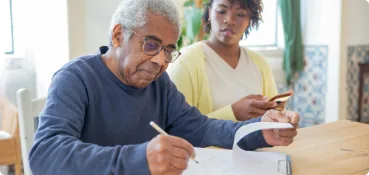 img-our-story-4 A care manager in Northern Virginia helps a client with paperwork